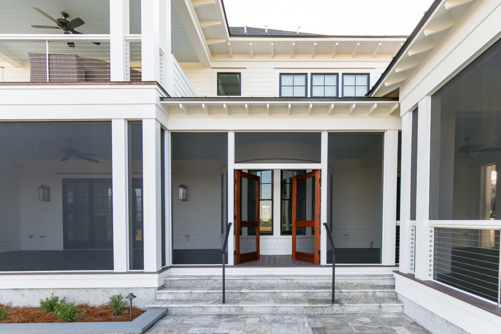 Luxury Lowcountry home with screened porch, white siding, and wooden doors in Charleston, SC.